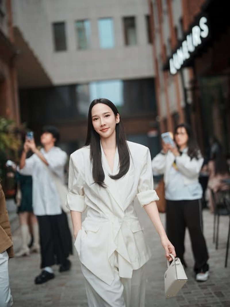 中国で撮影した白いスーツ姿のアウム・パチャラパー。周囲にカメラを構える人々がいる