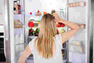 ผู้หญิงยืนมองตู้เย็น